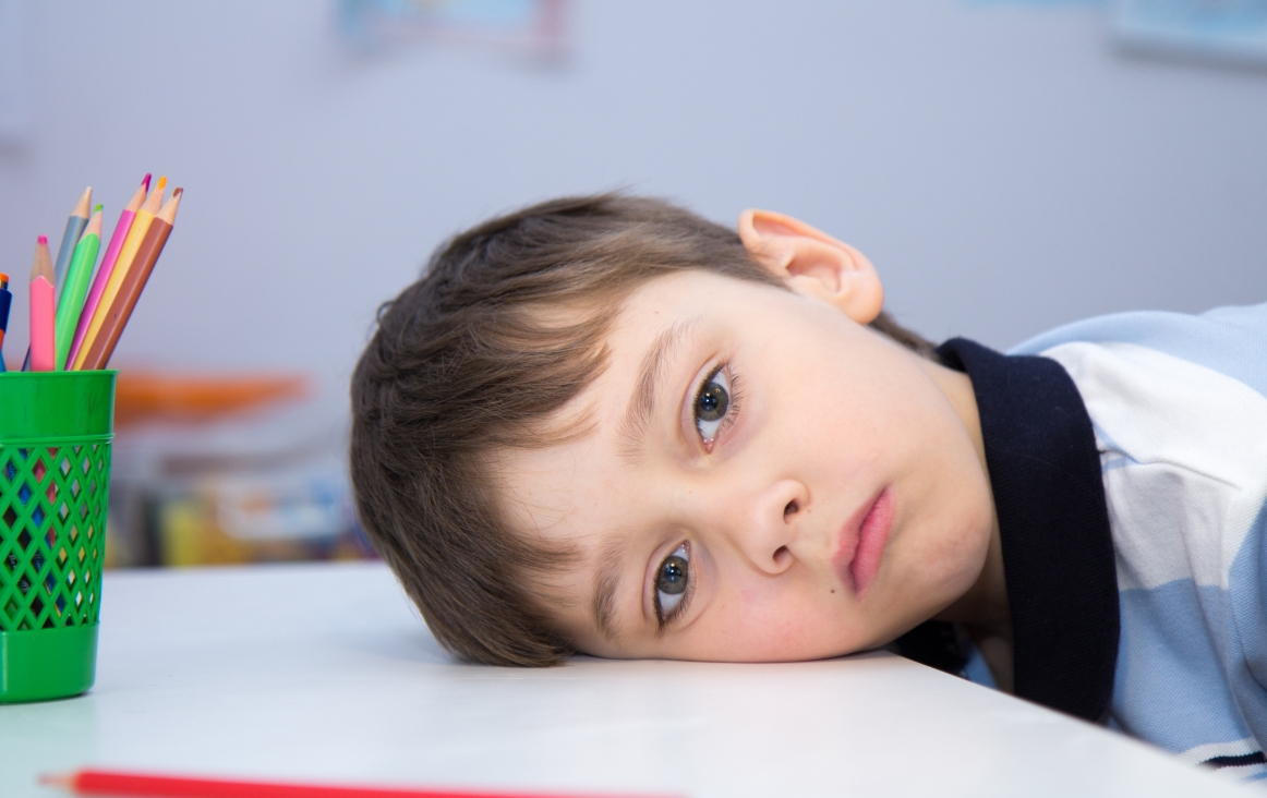 Foto van een balend kind met het hoofd op de lessenaar. Foto Shutterstock